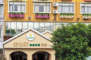 A building with a yellow facade, multiple windows, and a sign with a logo and Chinese characters. - Jindalai Tianyuan Hotel (Xing'an County)