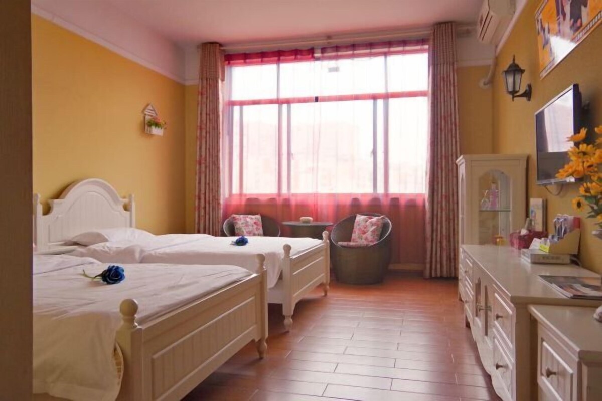 Een hotelkamer met twee bedden, een stoel, een bureau en een raam met gordijnen.