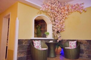 Un hall con dos sillones de mimbre, un arreglo floral y una pared de azulejos.