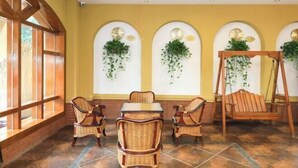 A room with a high ceiling, a ceiling fan, a table with chairs, a swing, and wall-mounted planters. - Jindalai Tianyuan Hotel (Xing'an County)