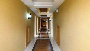 A long, narrow hallway with a wooden ceiling and walls painted in a light yellow color. - Jindalai Tianyuan Hotel (Xing'an County)
