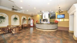 A reception area with a curved counter, wicker furniture, and a television on the wall. - Jindalai Tianyuan Hotel (Xing'an County)