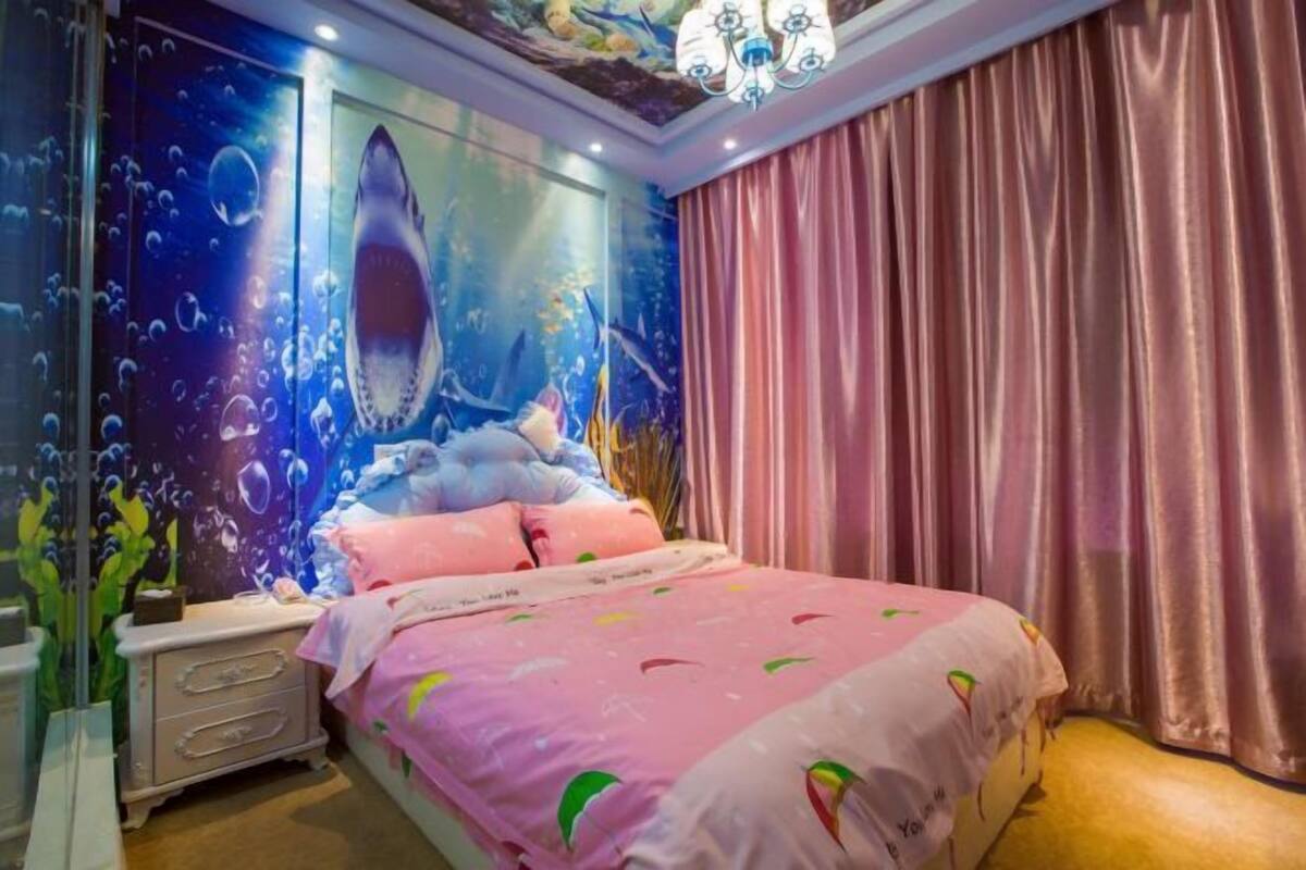 A bedroom with a bed, a nightstand, a wall mural, and a chandelier.