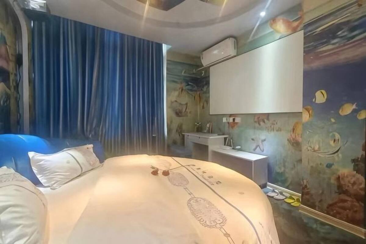 A bedroom with a bed, a vanity, and a wall mural.