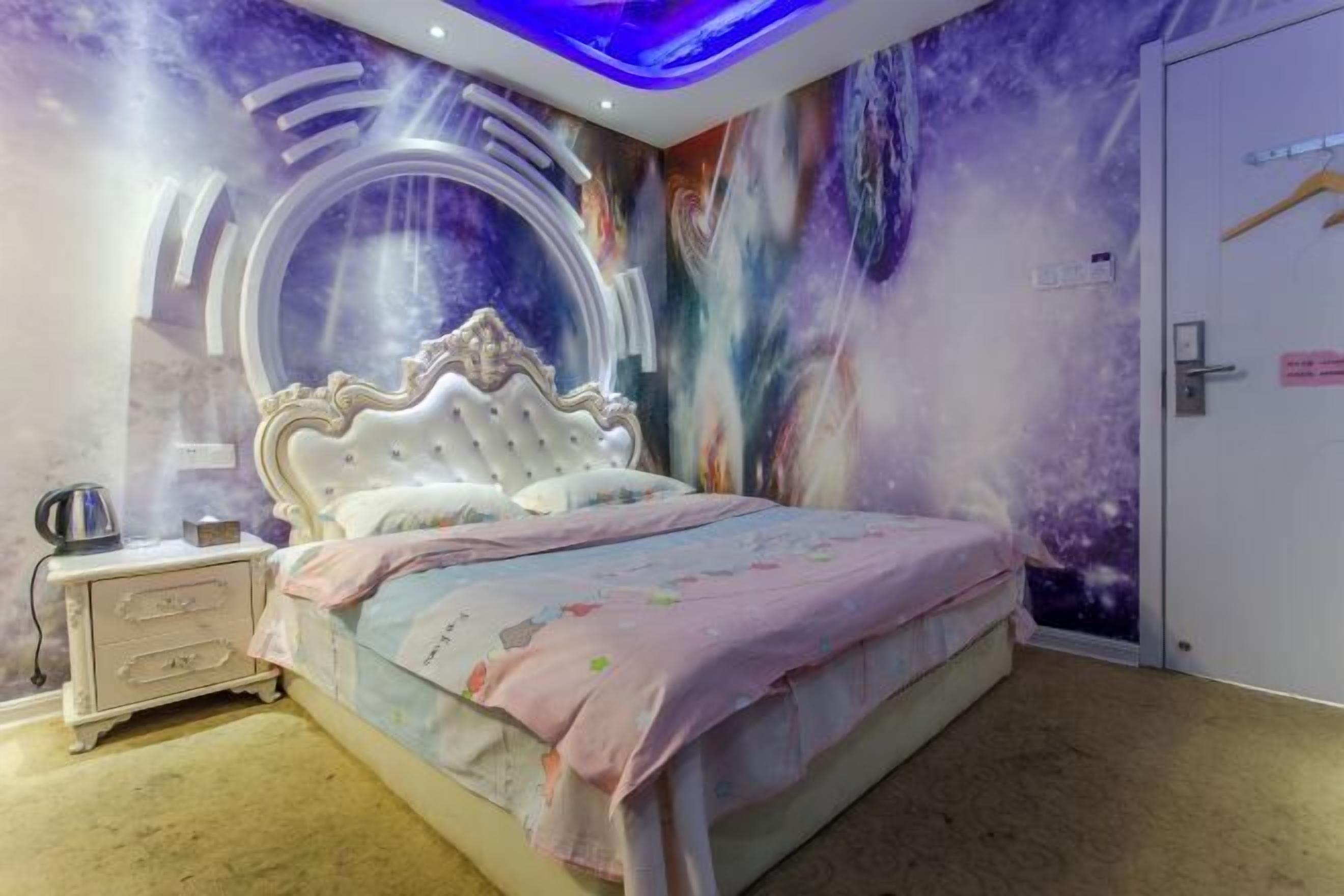 A bedroom with a bed, nightstand, and a wall mural.