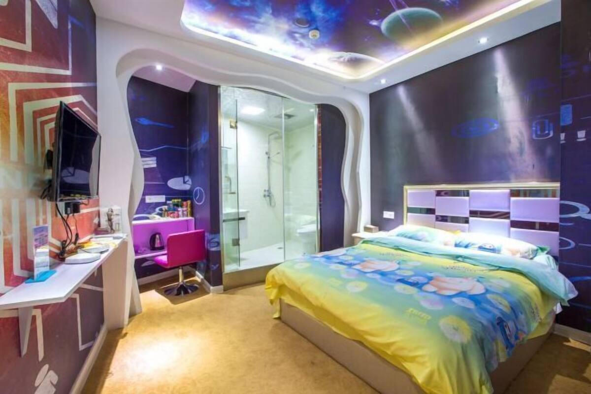 A modern bedroom with a bed, a vanity, a mirror, and a desk.