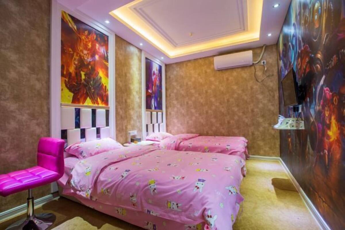A bedroom with two beds, a pink chair, and a ceiling with recessed lighting.