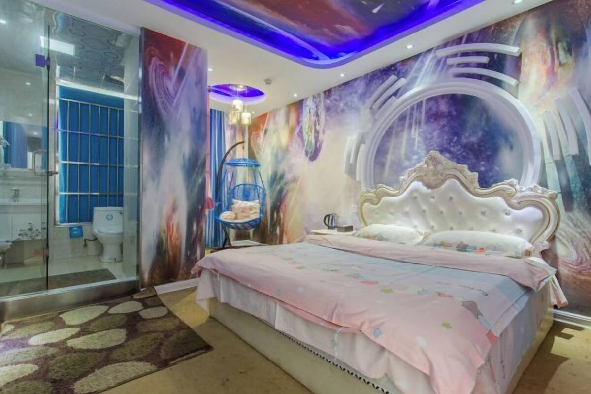 Ein Schlafzimmer mit einem großen Bett, einer Duschkabine aus Glas und einem Wandgemälde.