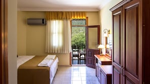 Une chambre d’hôtel avec un lit, un bureau, un miroir et une fenêtre avec des rideaux.