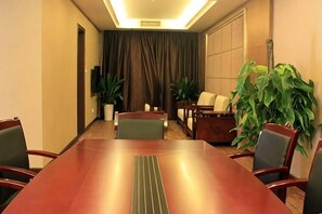 A conference room with a long table, chairs, a sofa, and potted plants. - Hanshou Inn (Guangyuan)