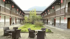 Pátio com mobiliário ao ar livre, um jardim central e arquitetura tradicional.