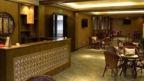 Um hall de hotel com balcão de recepção, área de estar e um espelho grande.