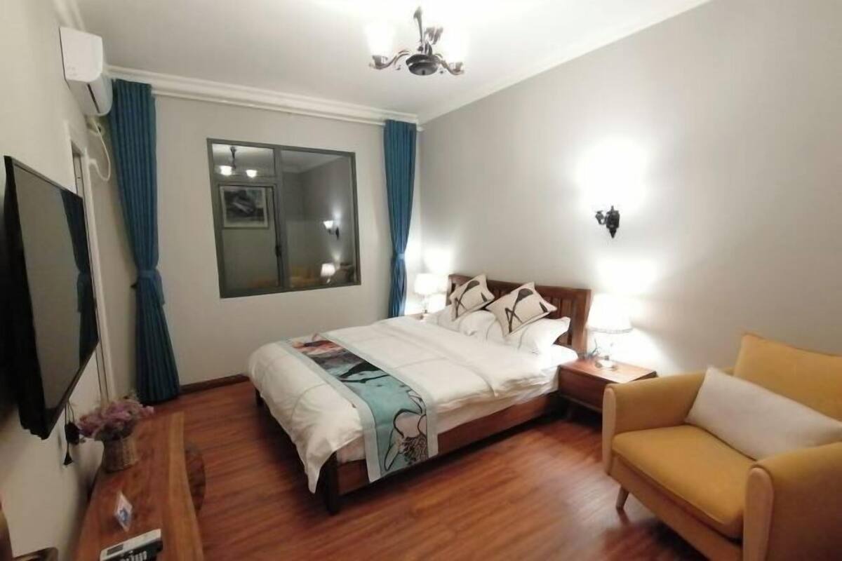 A hotel room with a bed, a sofa, a TV, and a window with curtains.