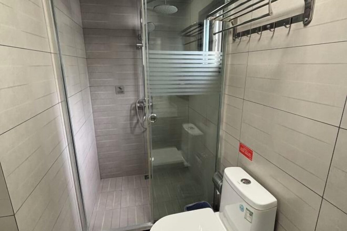A bathroom with a glass shower enclosure, a toilet, and a hand dryer.