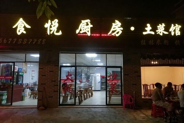 A restaurant with a neon sign, glass doors, and indoor seating visible through the entrance. - Jingshe Hostel (Guilin)