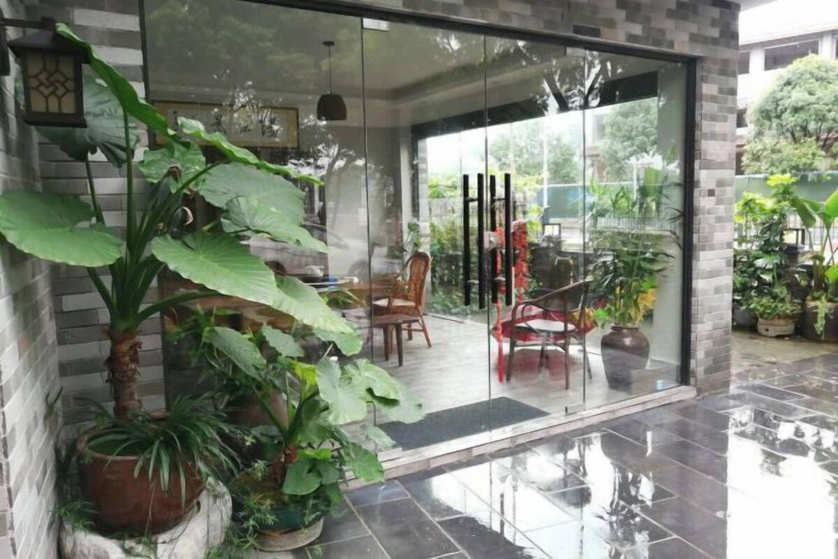 A modern interior with a glass door leading to a dining area, surrounded by potted plants.
