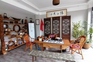 A traditional Chinese room with a wooden table, chairs, and shelves with pottery and decorative items. - Jingshe Hostel (Guilin)