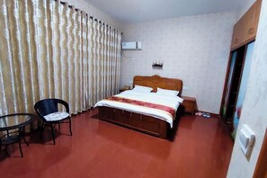A bedroom with a wooden bed, a chair, a small table, and a curtain. - Shuijutang Boutique Inn (Wuyuan)