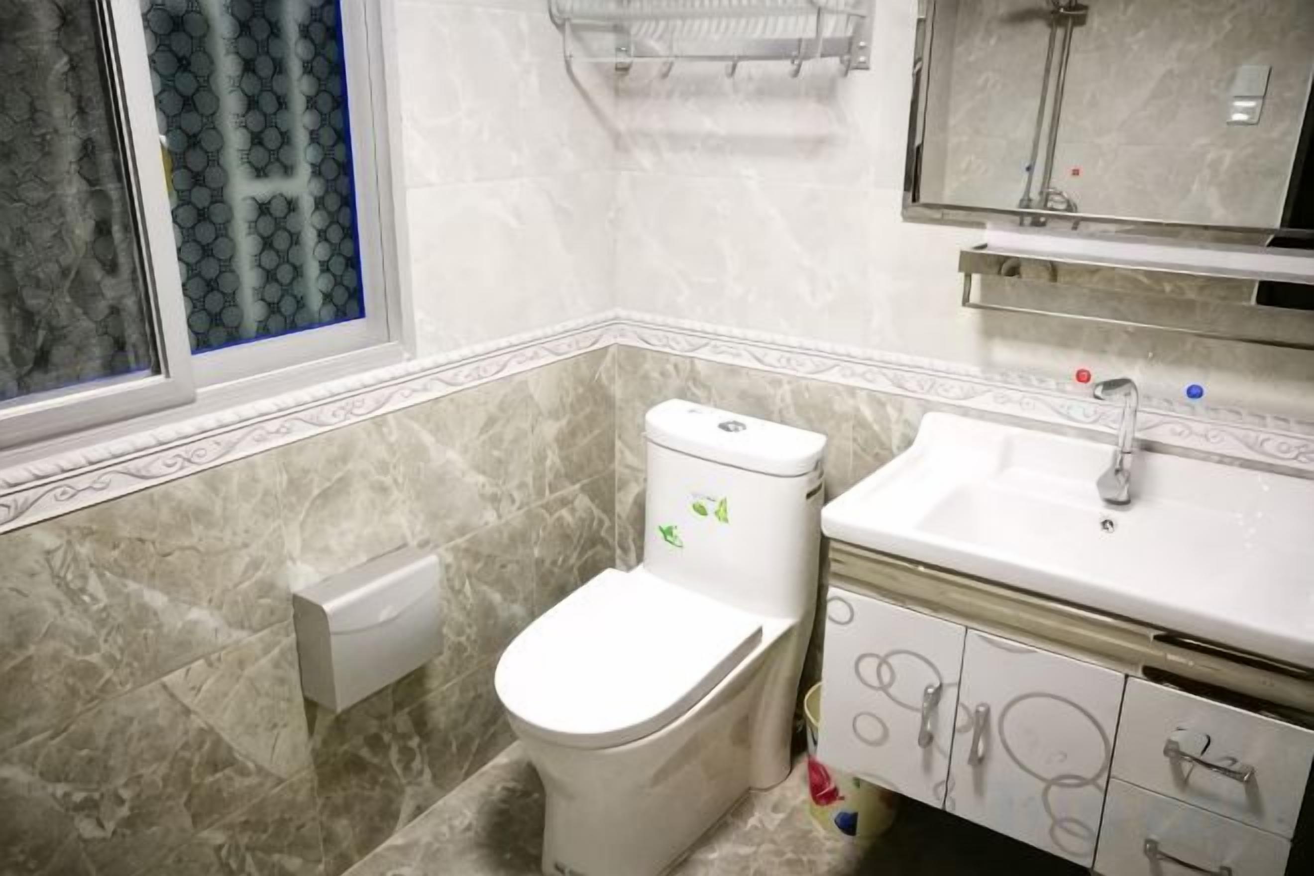 A bathroom with a toilet, sink, and mirror.