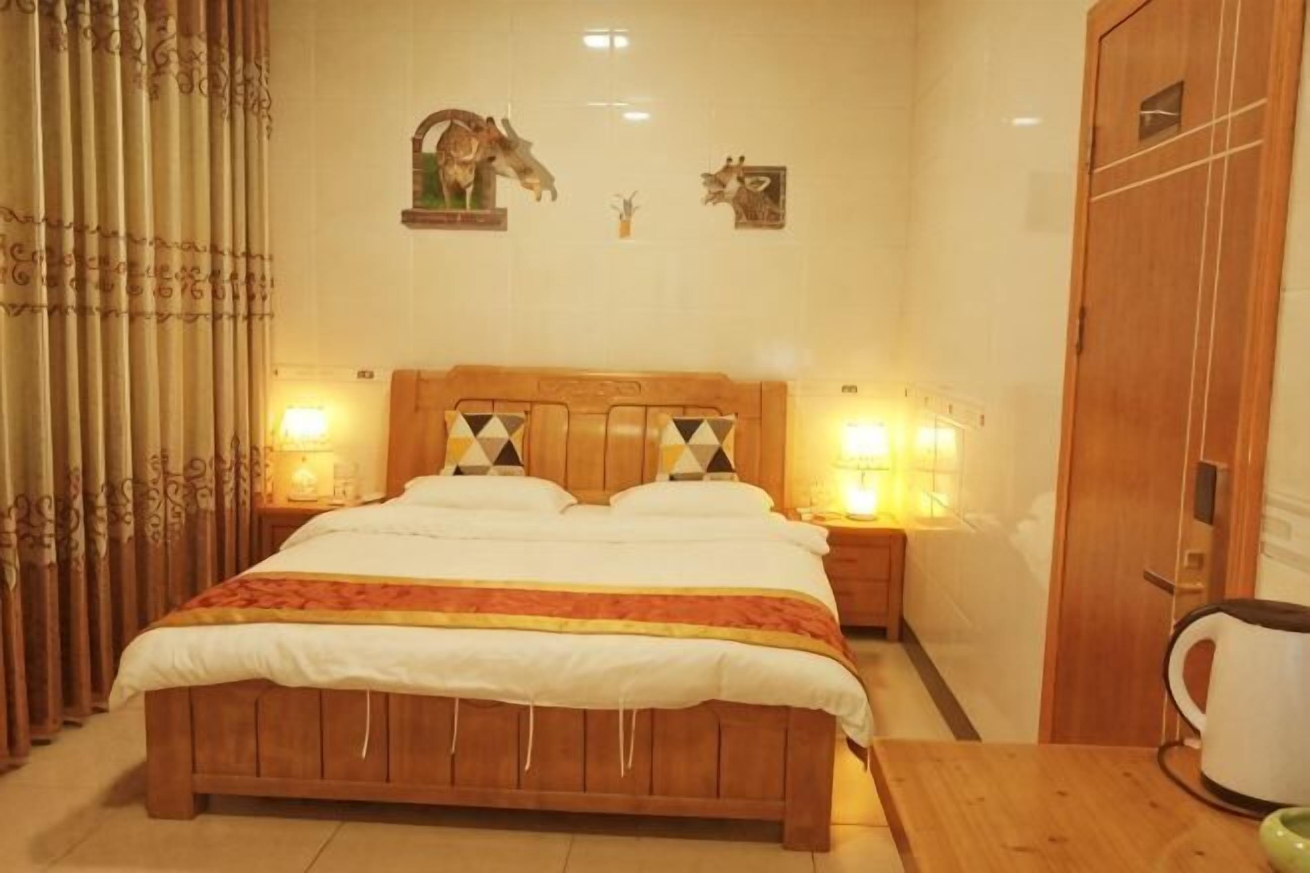 Un dormitorio con una cama de madera, dos mesitas de noche con lámparas, un armario de madera y una mesa de centro.