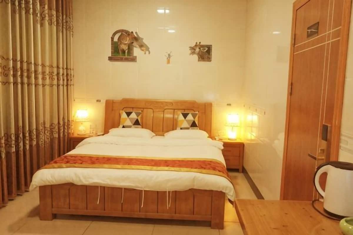 A bedroom with a wooden bed, two bedside tables with lamps, a wooden wardrobe, and a coffee table.