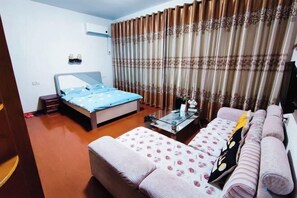 A bedroom with a bed, a sofa, a coffee table, and curtains. - Shuijutang Boutique Inn (Wuyuan)