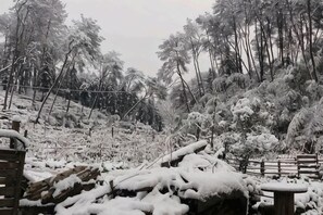 Un espacio exterior nevado con una valla de madera y un banco.