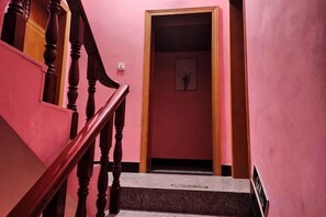 A staircase with wooden balusters leading to a room with pink walls and a framed picture on the wall. - Shuijutang Boutique Inn (Wuyuan)