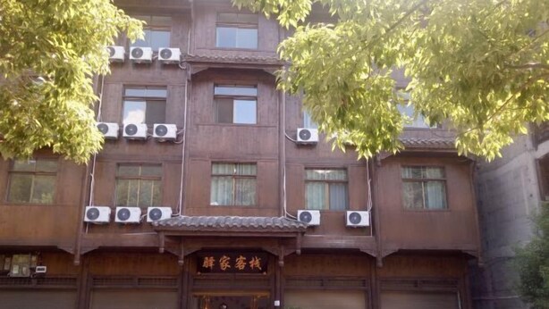 A multi-story building with a traditional architectural style, featuring multiple air conditioning units and a sign in a foreign language. - Yijia Inn (Chongqing)