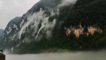 A mountainous landscape with a body of water in the foreground and a building on the left.