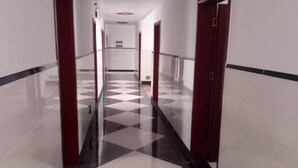 A corridor with a checkered floor pattern, glass railings, and doors with red frames. - Yijia Inn (Chongqing)