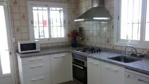 Cozinha com armários brancos, micro-ondas, fogão a gás e pia.