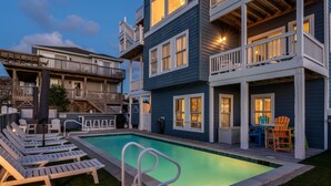 A pool area with lounge chairs, a small table, and a deck with chairs. - Luxury Semi-Oceanfront Escape with Private Pool (Corolla)