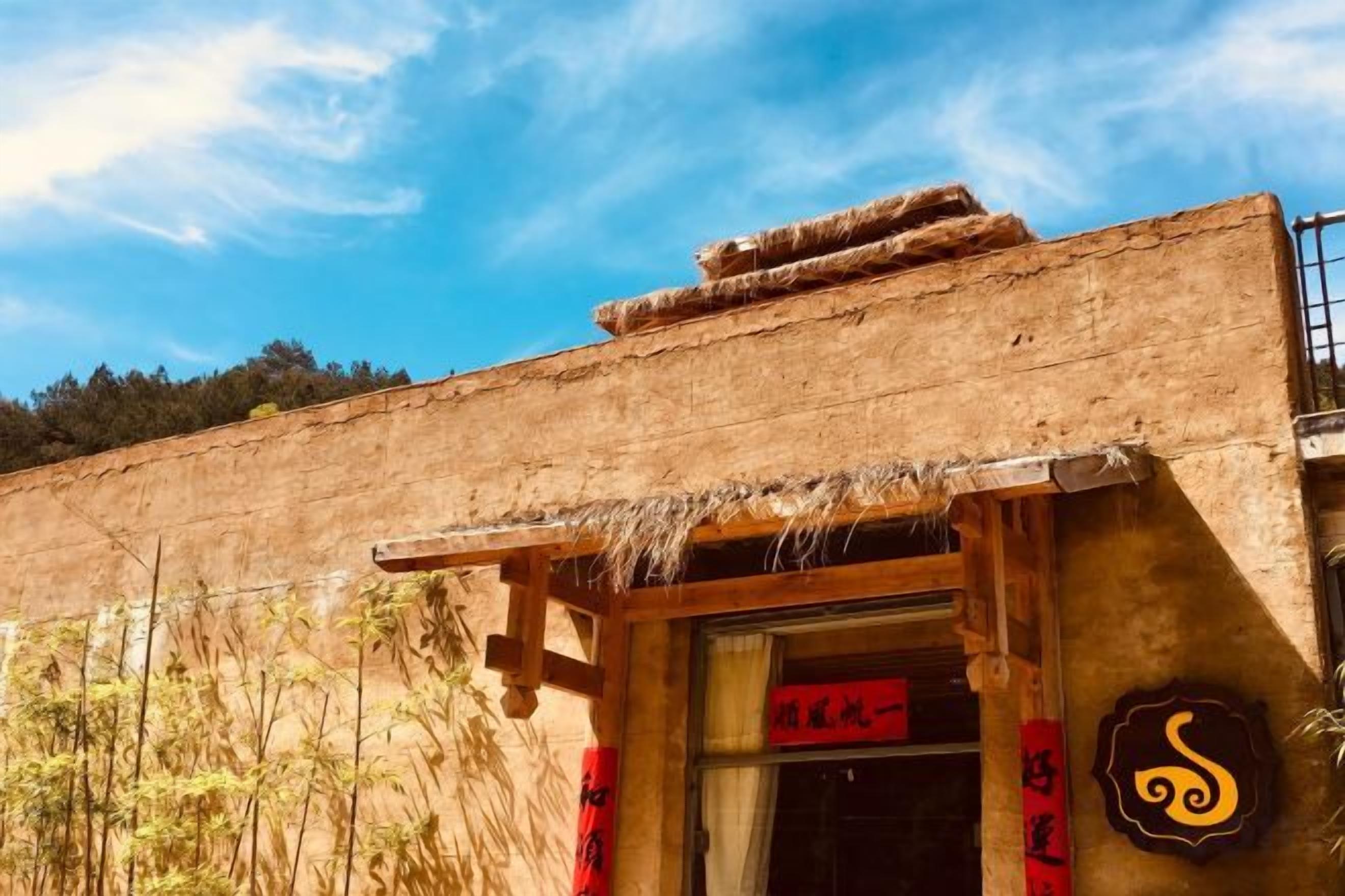 A rustic building with a traditional design, featuring a thatched roof and a wooden entrance.