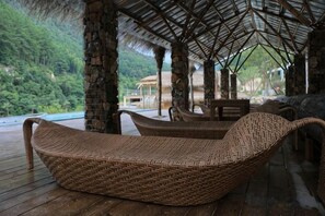 A covered outdoor seating area with wicker furniture and a view of lush greenery. - Youxi Guxi Galaxy Moon Mountain House (Youxi)