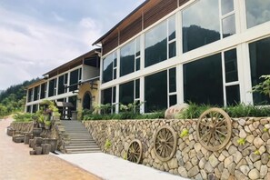 A modern building with large windows, a stone wall with decorative wheels, and a paved walkway. - Youxi Guxi Galaxy Moon Mountain House (Youxi)