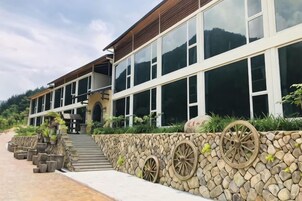 A modern building with large windows, a stone wall with decorative wheels, and a paved walkway.