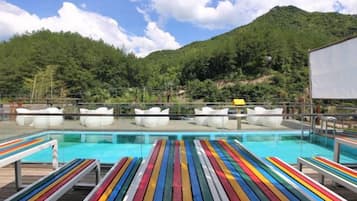 A pool area with lounge chairs and a view of a mountainous landscape.
