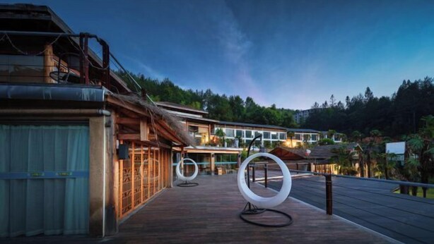 Ein modernes Hotel mit einer Holterrasse, großen Fenstern und Blick auf den umliegenden Wald.