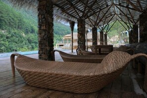A covered outdoor seating area with wicker furniture, a wooden deck, and a view of lush greenery. - Youxi Guxi Galaxy Moon Mountain House (Youxi)