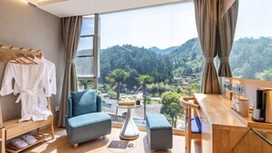 Ein modernes Hotelzimmer mit einem großen Fenster und Blick auf eine bewaldete Landschaft.