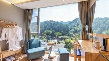 Una habitación moderna con un ventanal grande, un sofá azul, una mesita de madera y un perchero.