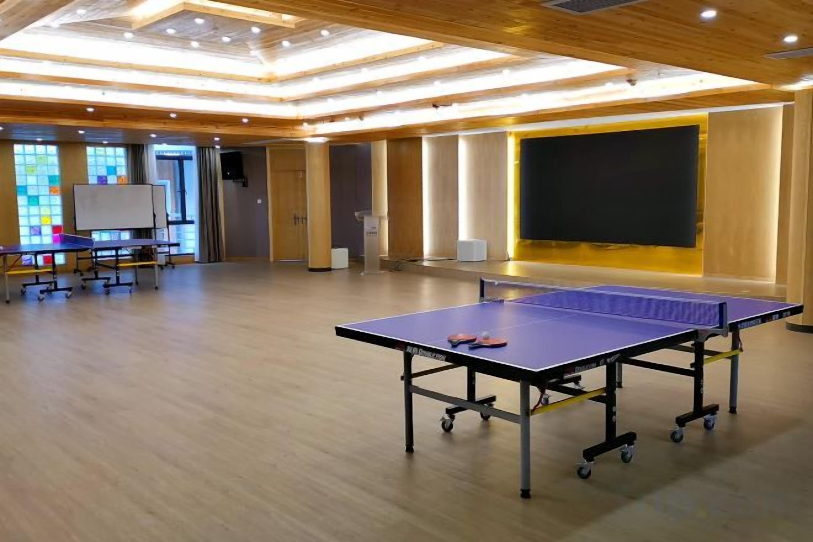 A room with a ping pong table, a whiteboard, and a projector screen.