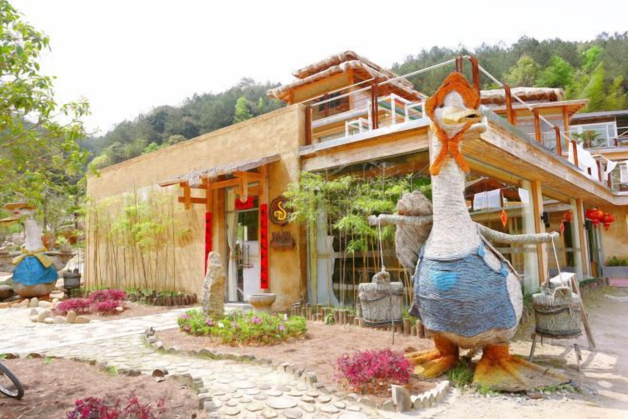 A building with a traditional architectural style, a large decorative bird sculpture, and a well-maintained garden with various plants and flowers.