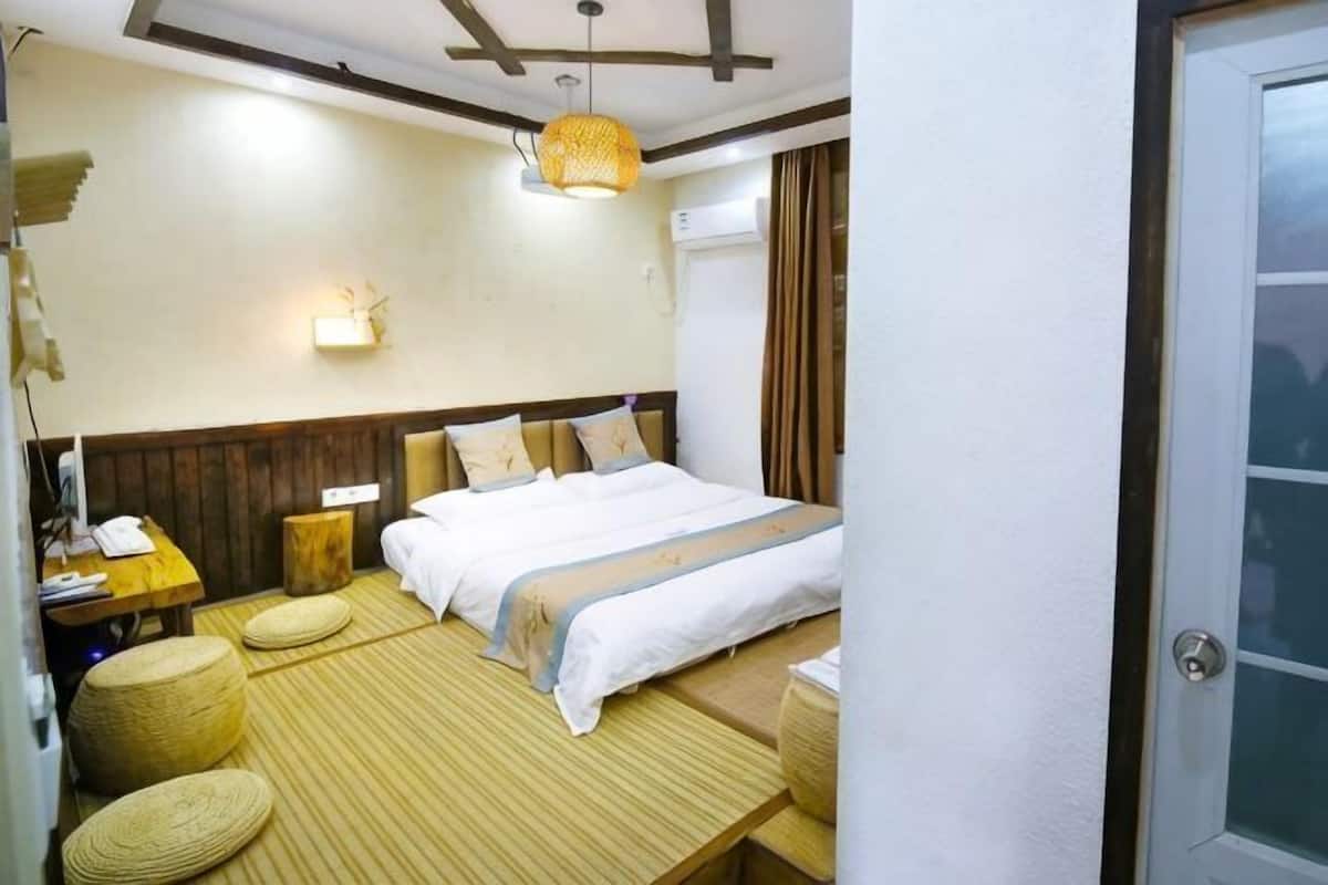 Una habitación de hotel con cama, mesita de noche, lámpara y un pequeño rincón de descanso con mesa y sillas.