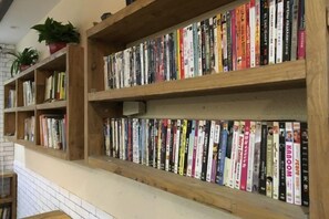 Une bibliothèque remplie de livres, avec des étagères en bois et une plante en pot.
