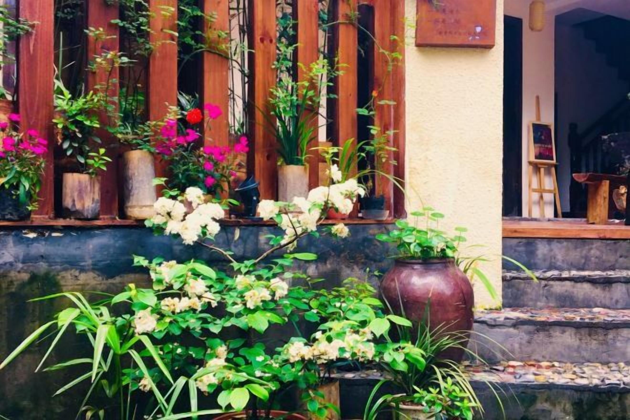 Un escalier en bois mène à une porte, et un pot de fleurs est placé sur l’une des marches.