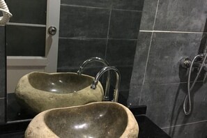 Et badeværelse med to stensinkevaske, et spejl og en bruser.