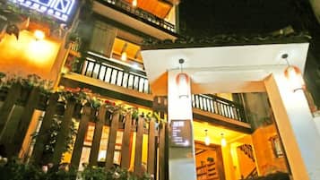 A hotel entrance with a covered walkway, a balcony, and a sign with Chinese characters.