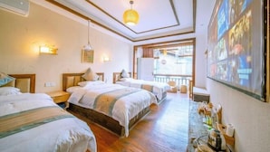 A hotel room with three beds, a wooden floor, a balcony, and a wall-mounted projector.